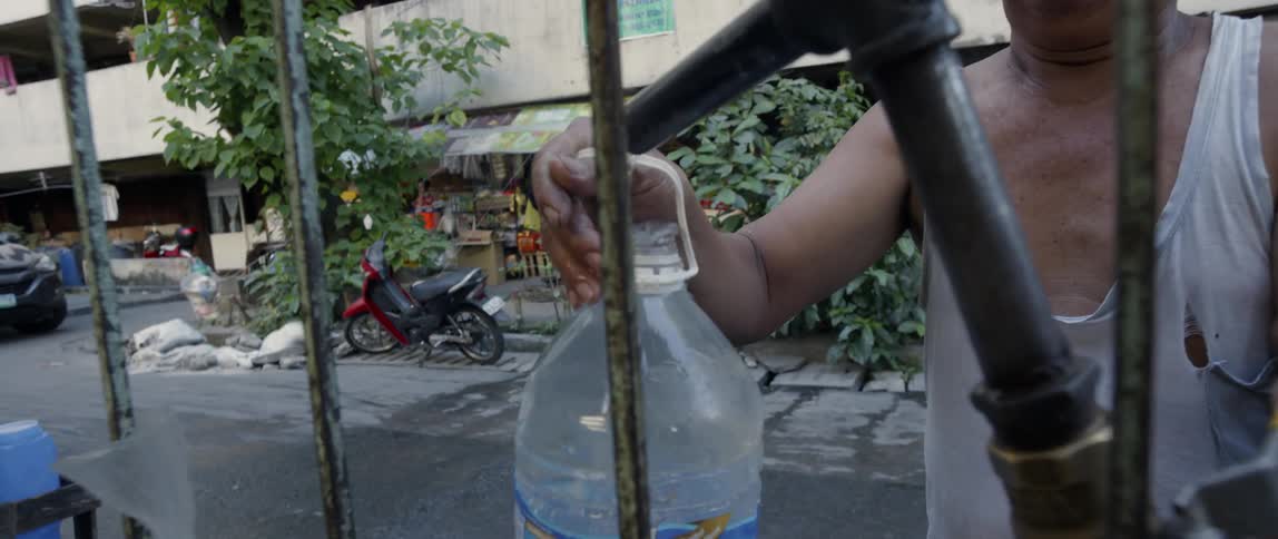 Man fills a bottle with water at an outdoor tap