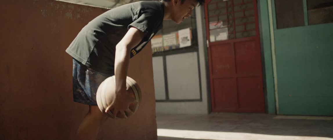 Boy is dribbling basketball through his legs