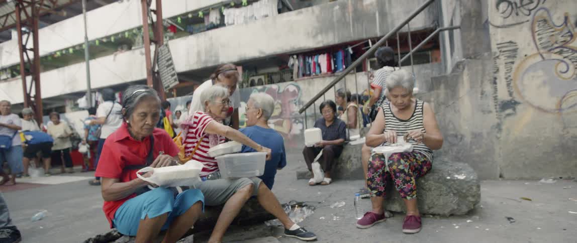 People are gathered together by the building eating