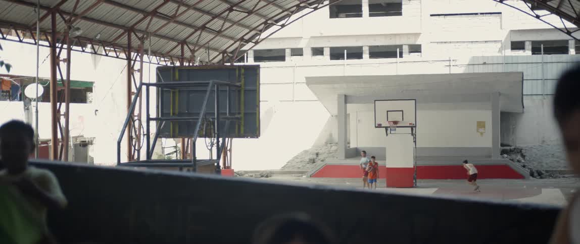 Young men toss a basketball at a hoop attached to a backboard