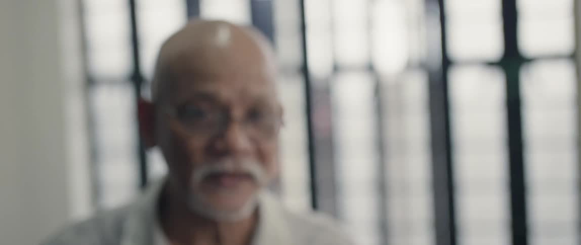 Elderly man sits next to a window