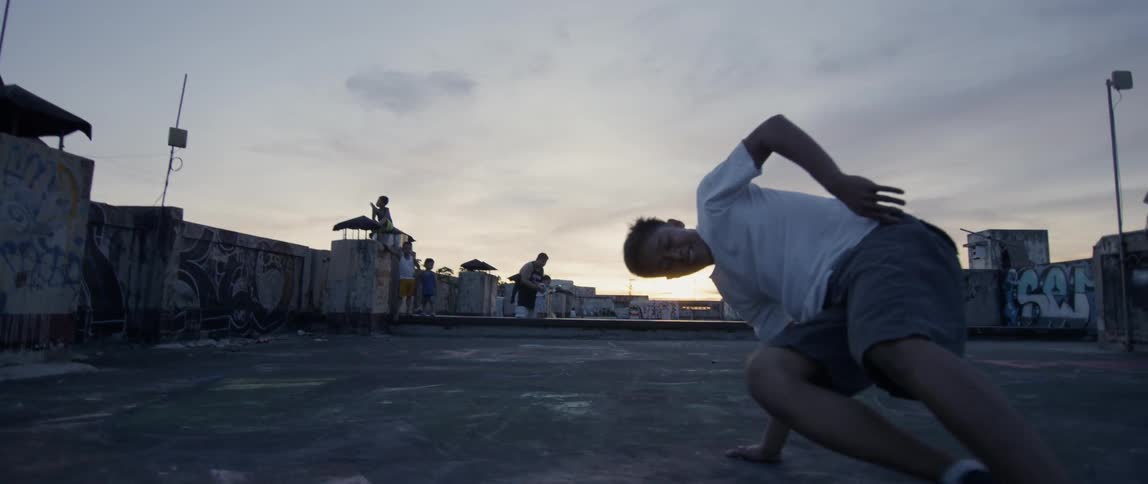 Teenager break dances outside at sunset