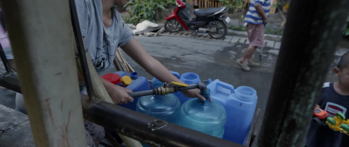 The person is filling the containers with water from a hose