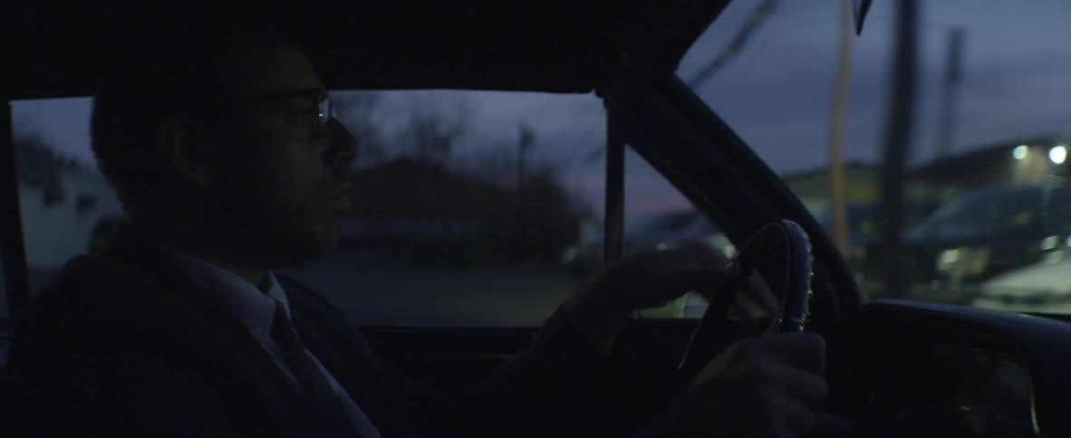 A man in a suit driving a car at night