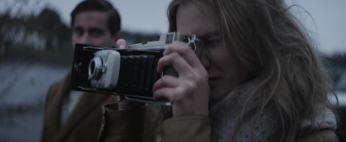A woman taking a photograph with an old camera while a man looks on