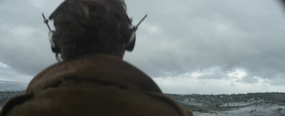A man with headphones standing in a snowy field