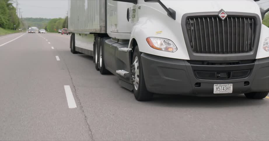 A semi-truck is driving on a highway during the day