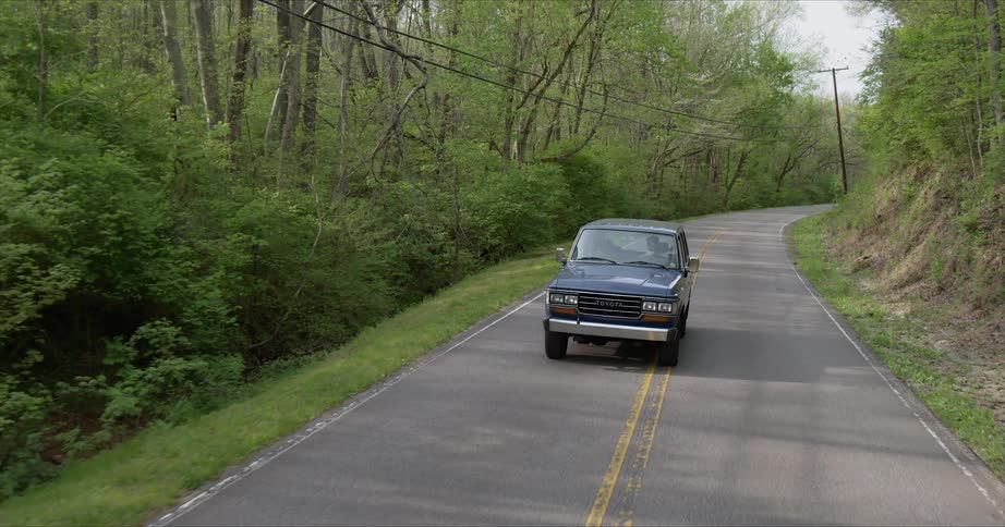 An old pickup truck is driven on a rural road