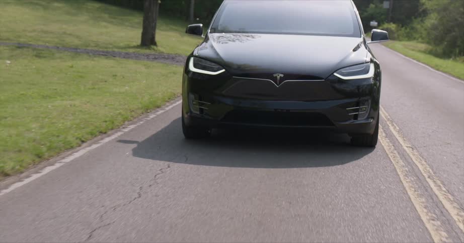 The black car drives on the small road