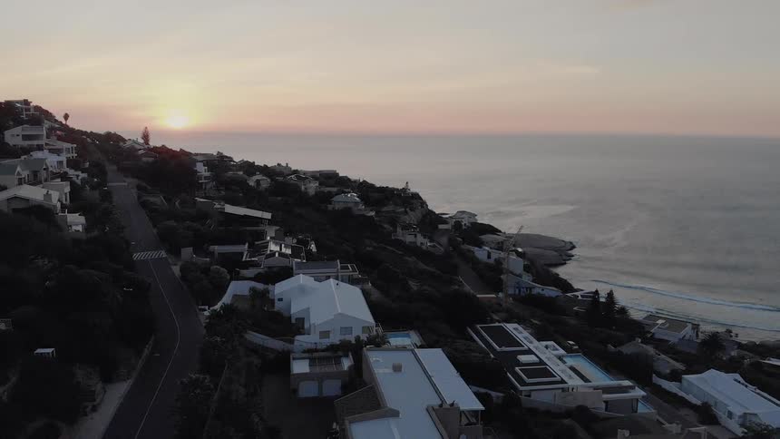 The sun sets over a coastal city