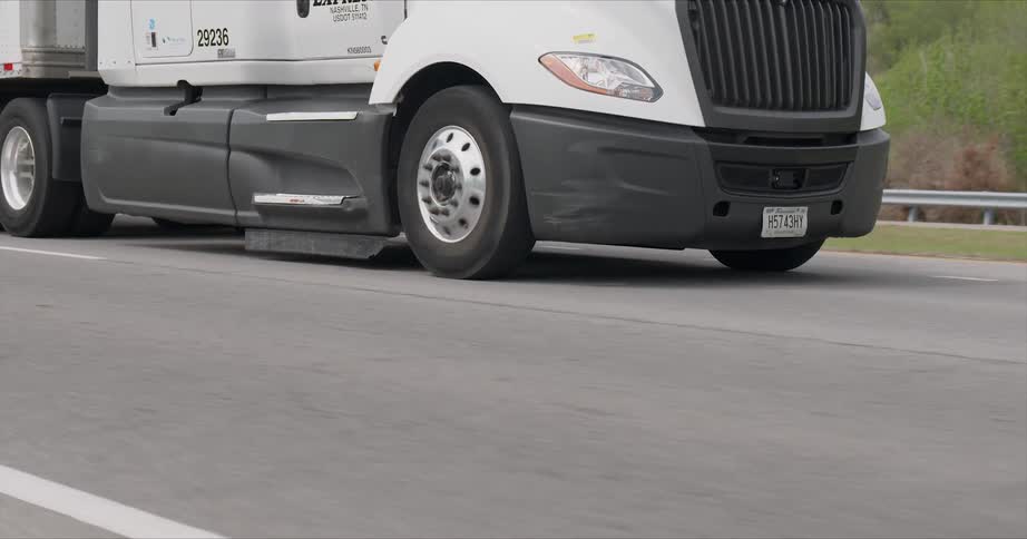 The truck is pulling a trailer on the road