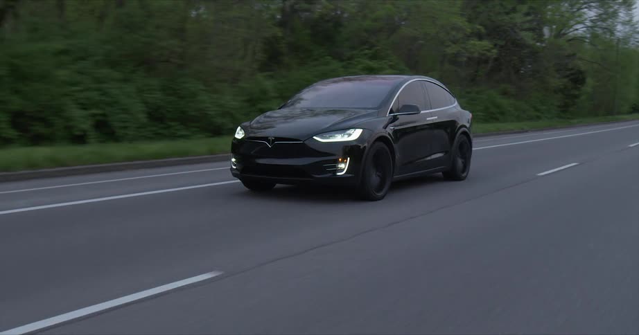 A car with headlights on travels on a rural road