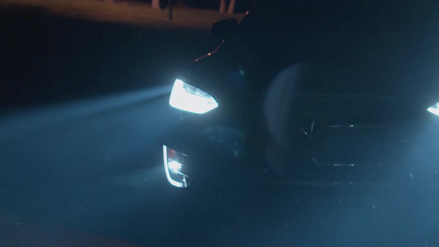 The car is driving down the road with bright headlights at night