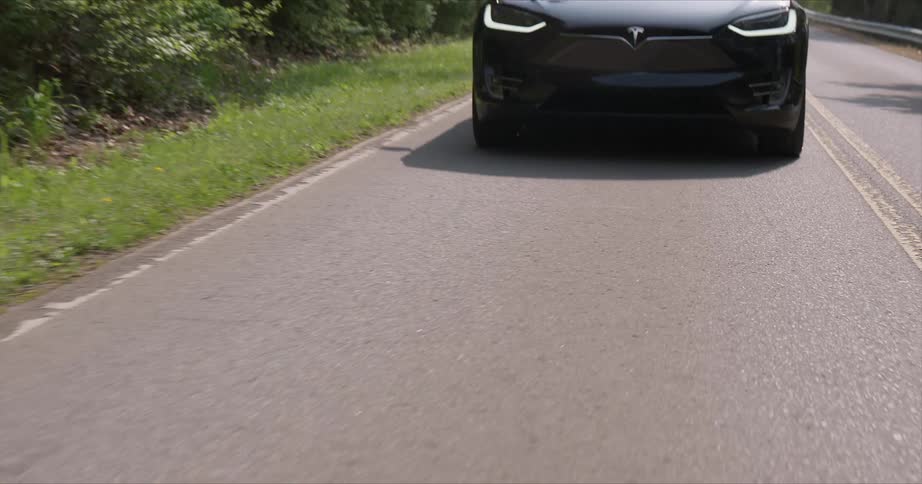 Black car travels on the road near a forest