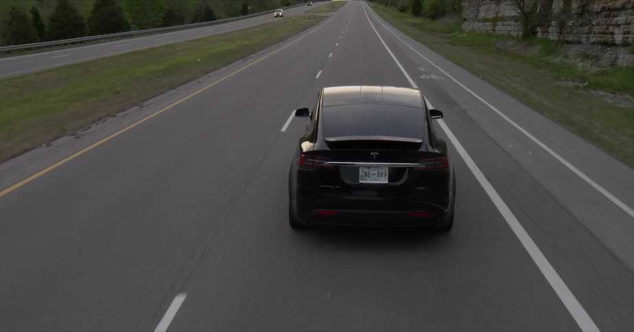 A tesla car rides on the highway road