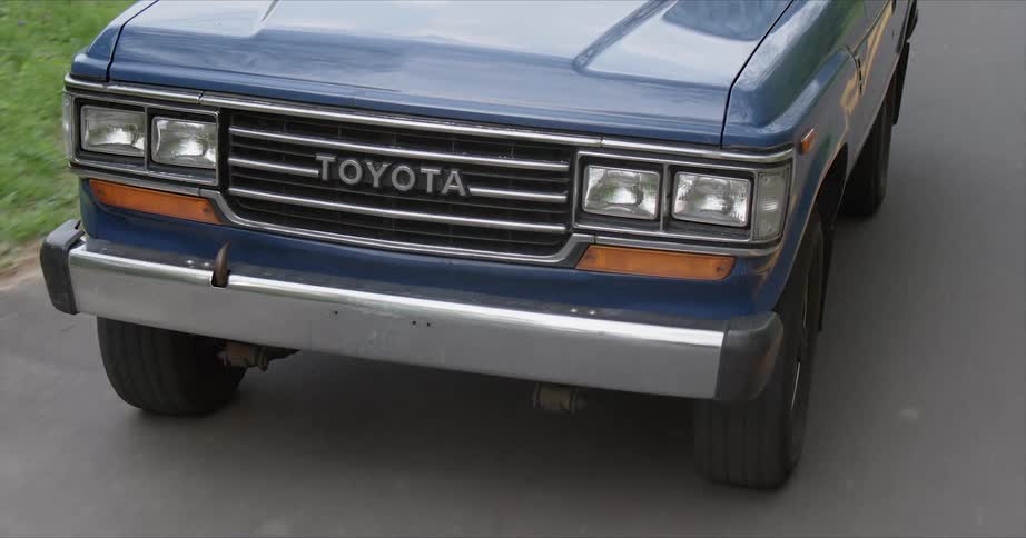 An old toyota pickup is driven on a rural road