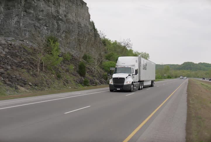 A semi-truck is driving on a highway during the day