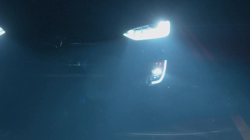 Headlights from a vehicle shine on a road at night