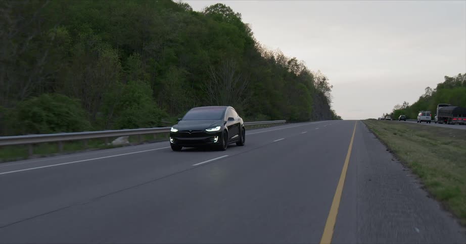 Black tesla is traveling on highway in the evening