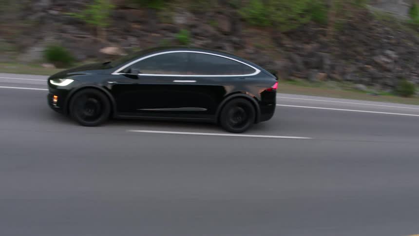 Black tesla car is traveling on highway