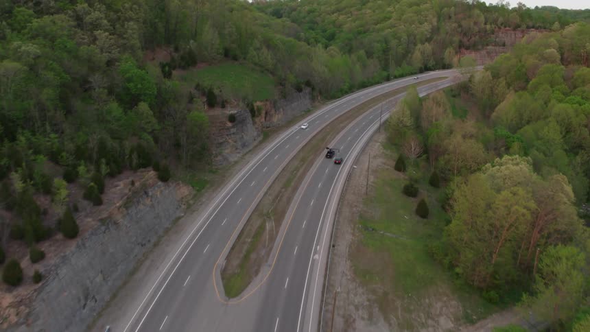 Cars travel down the highway by the woods