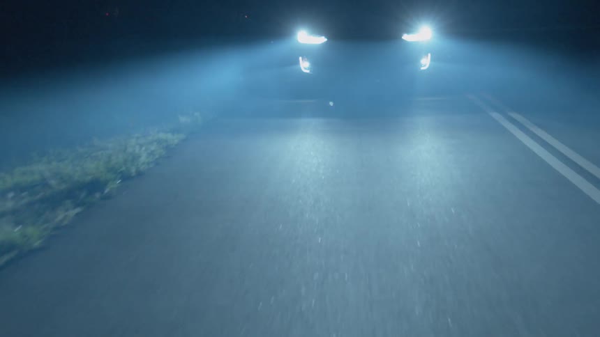 Car drives through fog at night