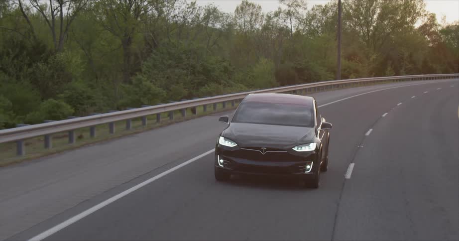 Black car travels down the highway near the trees
