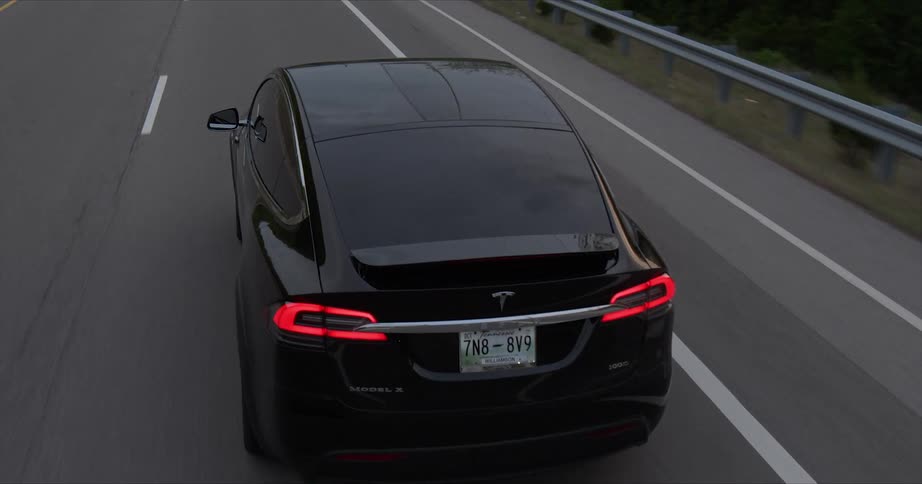 A black car drives on the highway