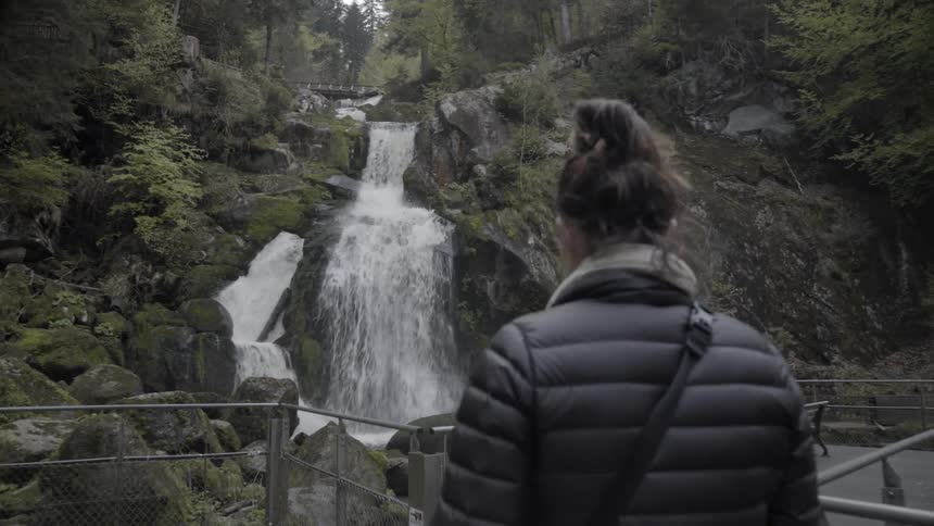 Woman photographs a waterfall while hiking in mountains