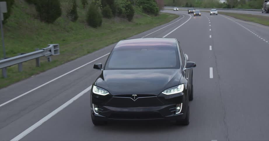 The car is driving down the road near the field