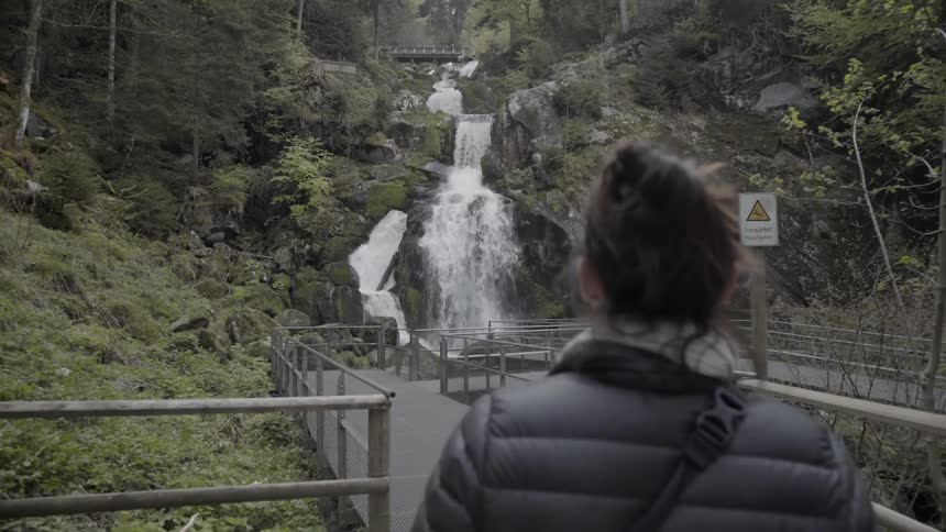 Woman hikes near a waterfall in mountains
