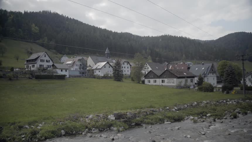 A river is flowing past a village on a cloudy day