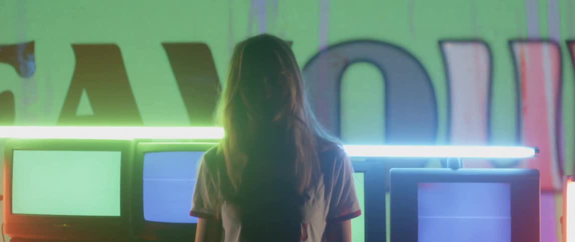 Woman stands in front of many screens flashing different colored lights