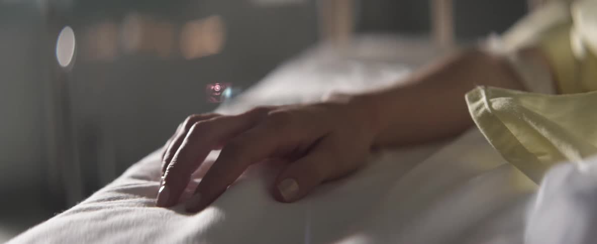 Hand of a hospitalized person begins to grasp the blanket