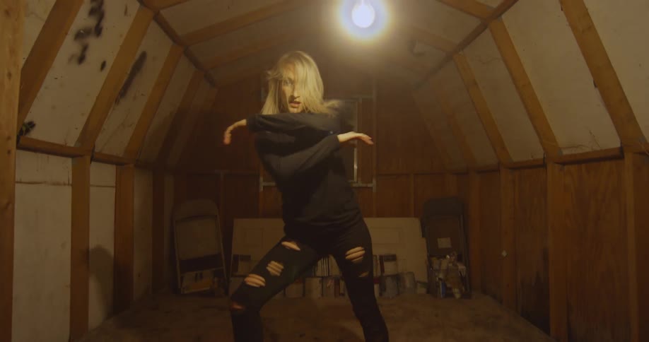 A woman is dancing inside an attic space at night
