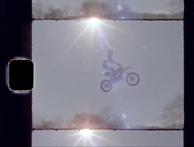 The person jumps high on the hill on a dirt bike