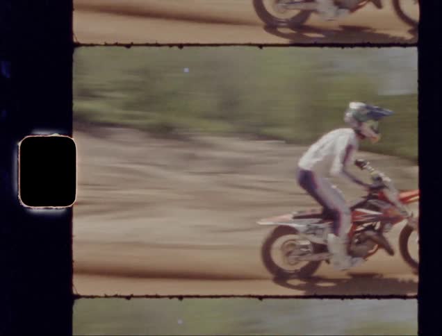 Person rides a dirt bike over two tall dirt hills