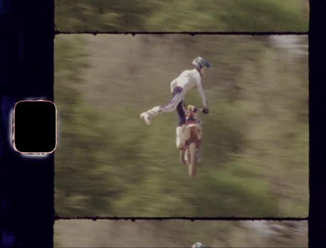 Man riding a dirt bike rides over a ramp and flies through the air