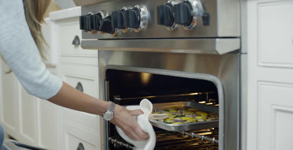Woman removes food from an oven