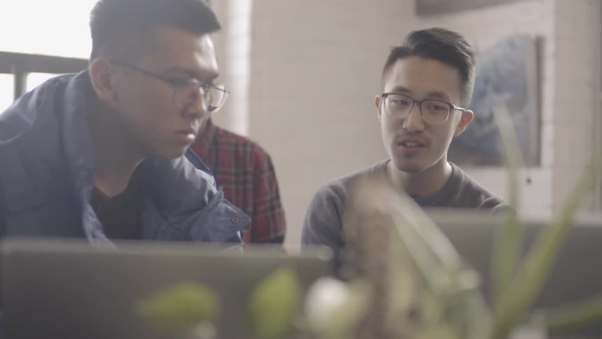 Coworkers talk while looking at a laptop