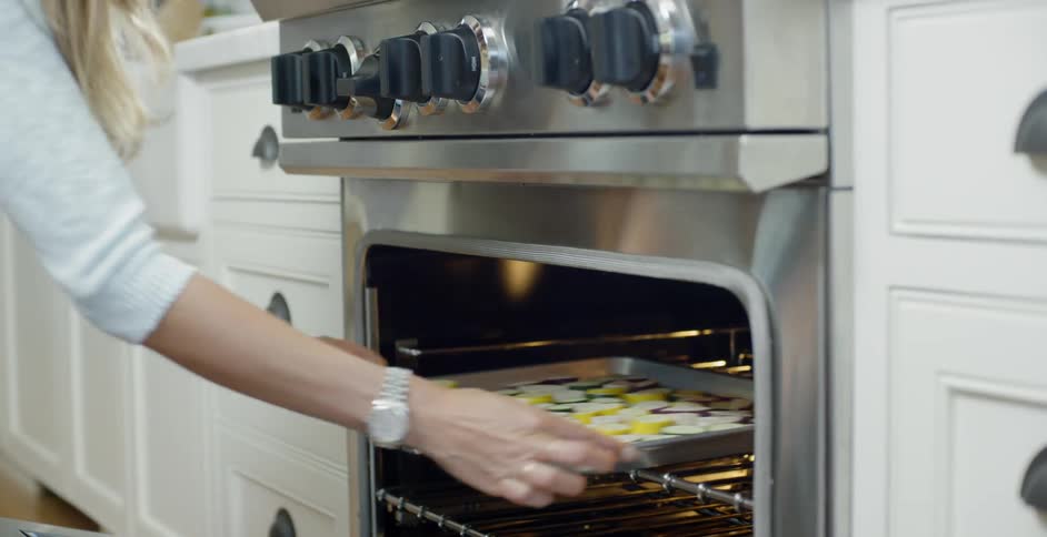 A woman puts food in the oven to cook