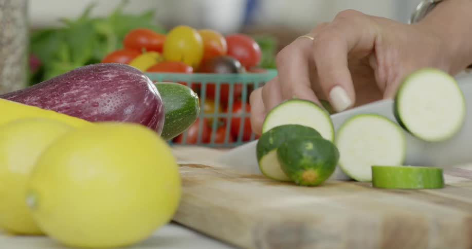 Woman is chopping vegetables on cutting board in kitchen