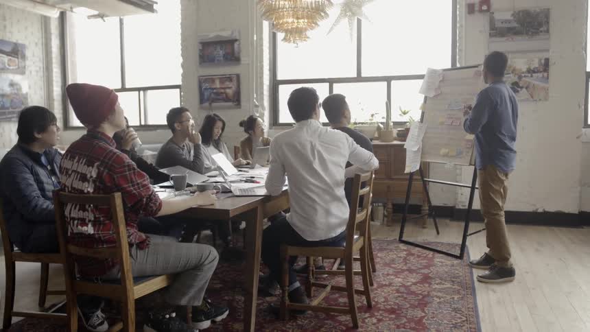 People are seated around a table watching a presentation