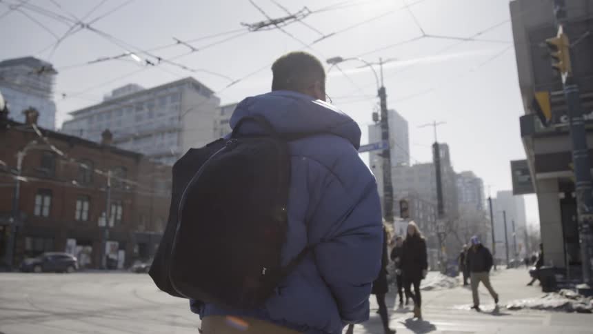 A man is crossing an urban intersection on a winter day