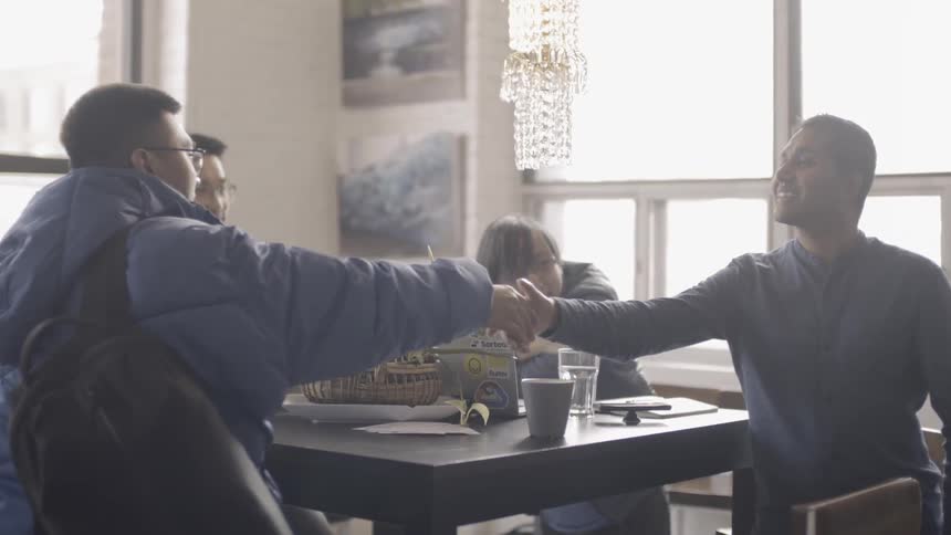 Two men shake hands indoors