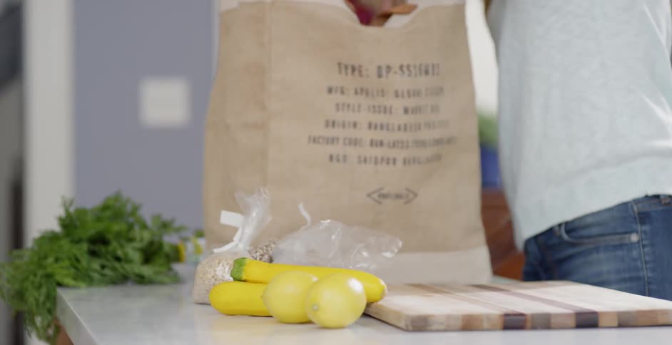 A woman is unpacking some groceries in the kitchen