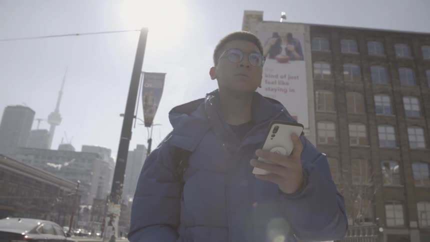 Man uses his phone while walking on a city sidewalk