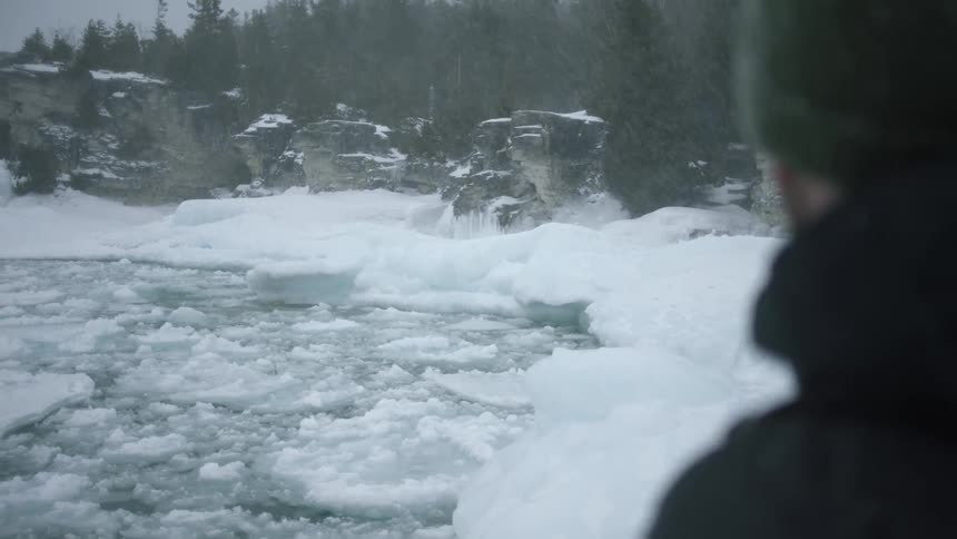 The shore is covered with ice as it snows