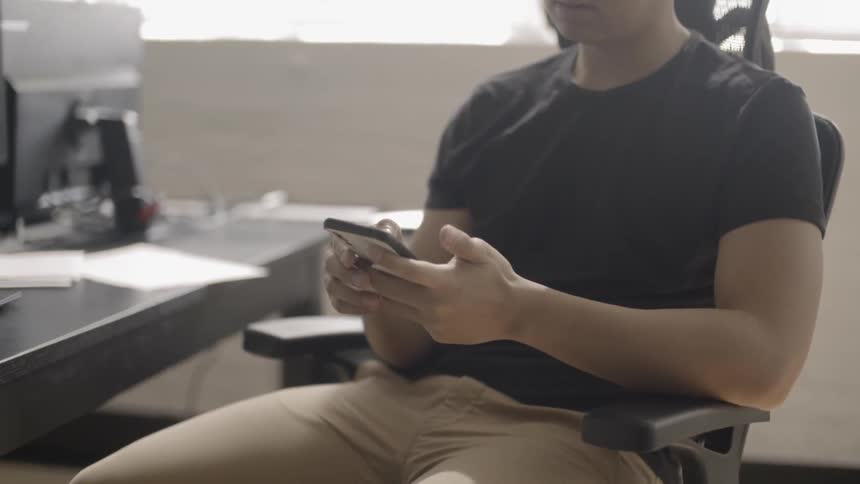 Man looks at his phone in an office chair