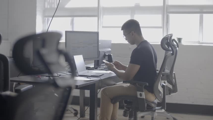 A man answers his phone in an office room